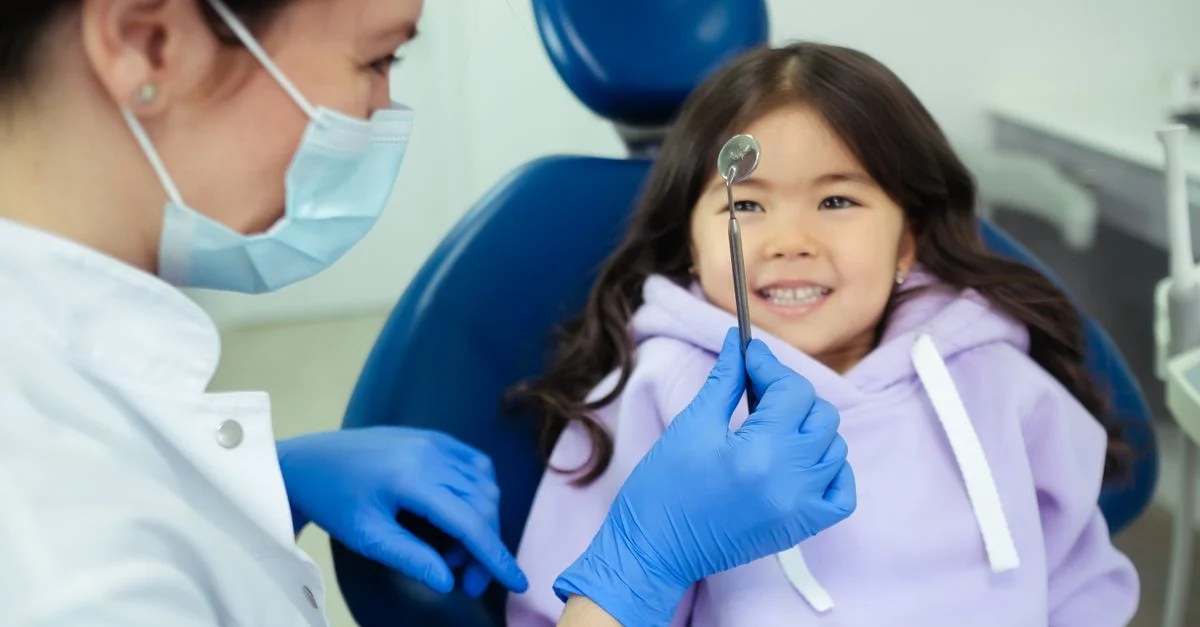 Un dentiste et un enfant souriant lors d'un contrôle dentaire amical dans une clinique.