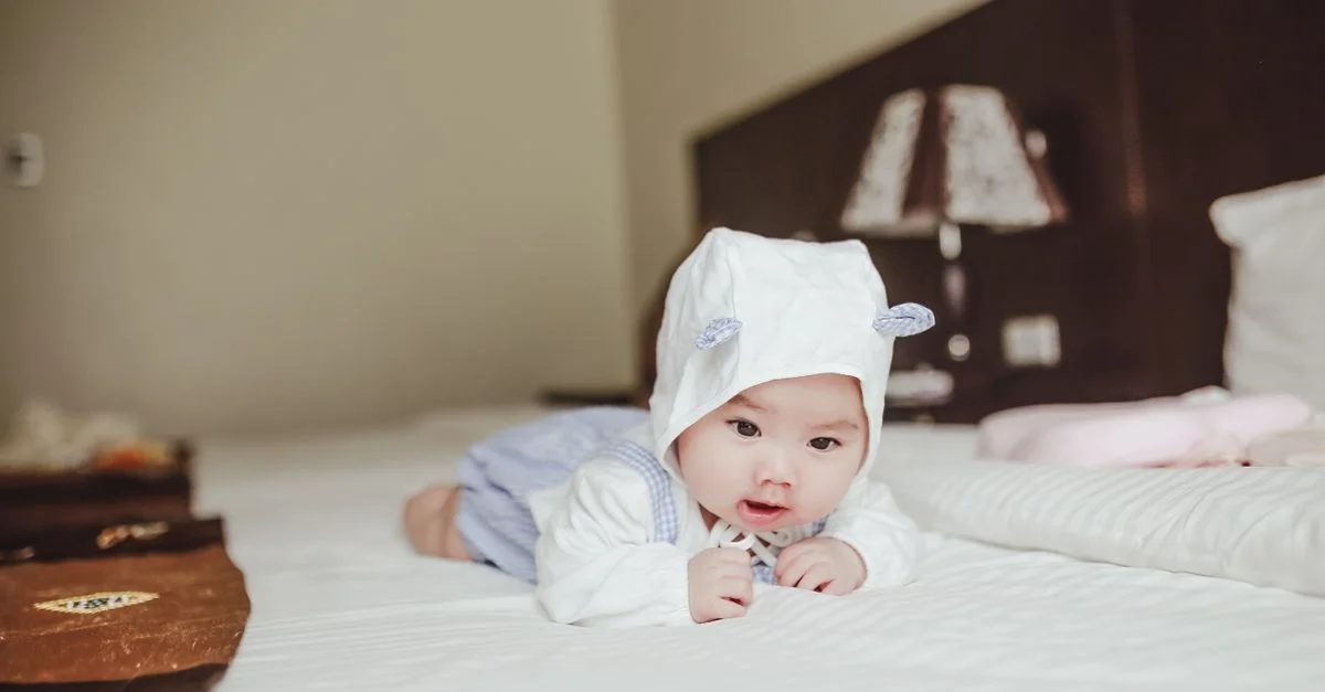 Un lindo bebé con un gorro blanco acostado en una cama, exudando inocencia y tranquilidad.