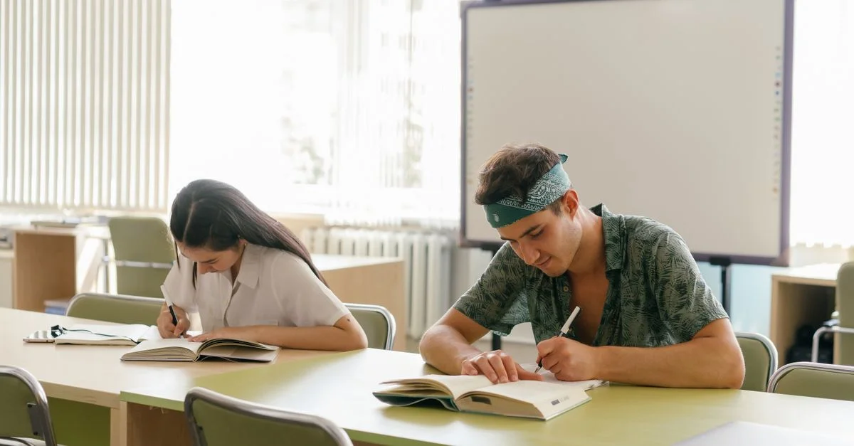 Dos estudiantes concentrados en el estudio en un aula moderna y luminosa.