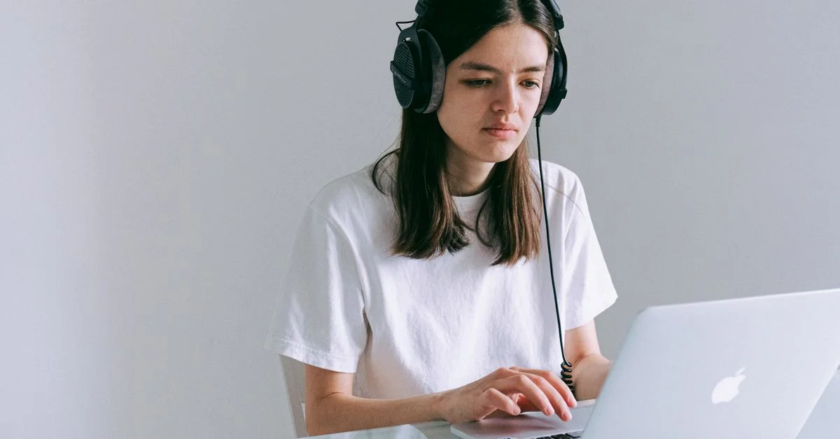 Una mujer en una oficina en casa trabajando en su portátil con auriculares. Perfecto para representar trabajo remoto y tecnología.