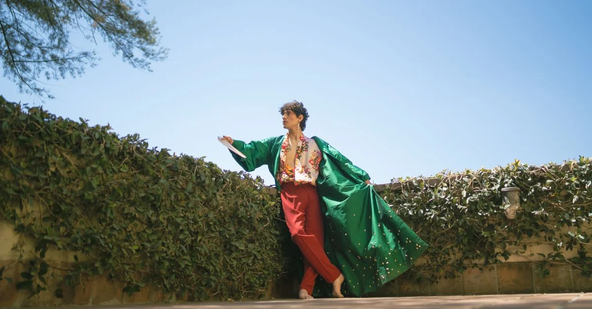 Individuo elegante con un kimono moderno y vibrante posa frente a un fondo natural, mostrando un estilo de moda contemporáneo.