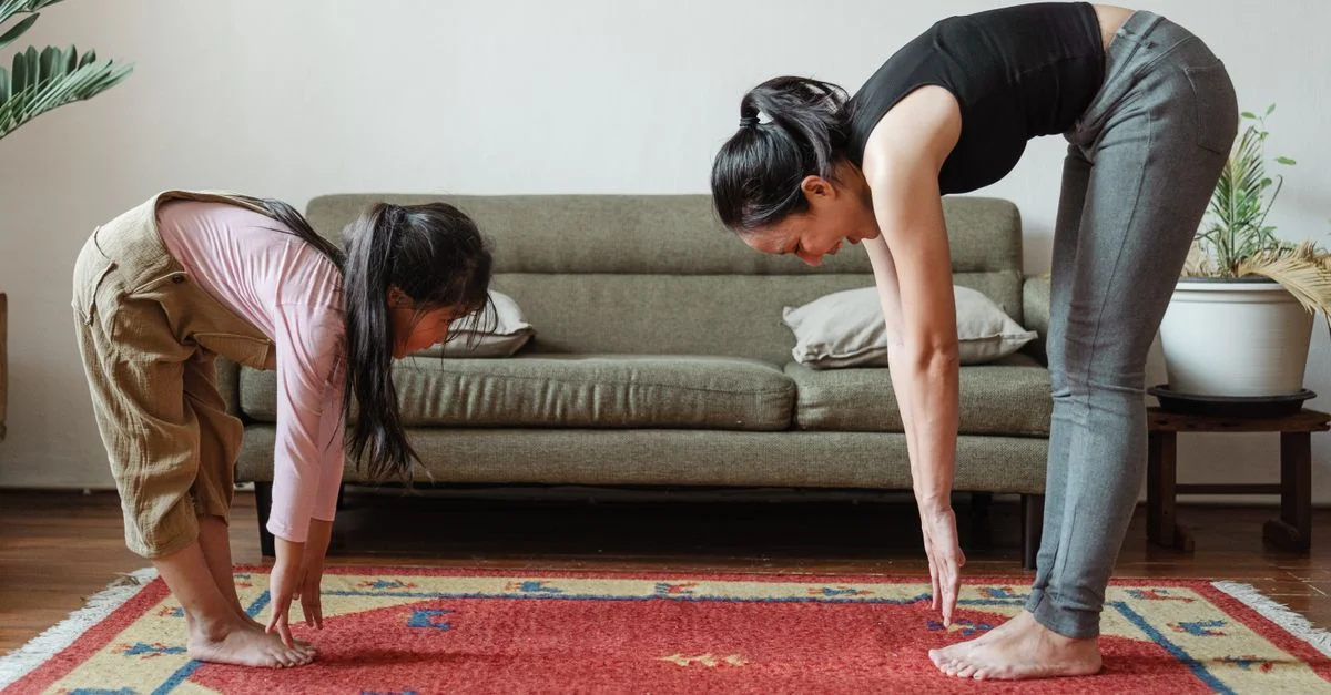 Une mère et sa fille pratiquant le yoga et des exercices d'étirement ensemble dans le salon.