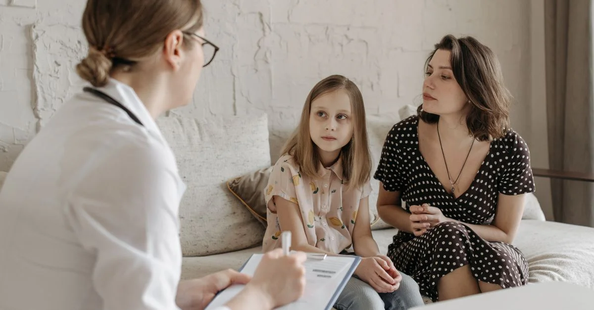 Una madre y su hija consultan con un médico durante una cita médica en interiores.
