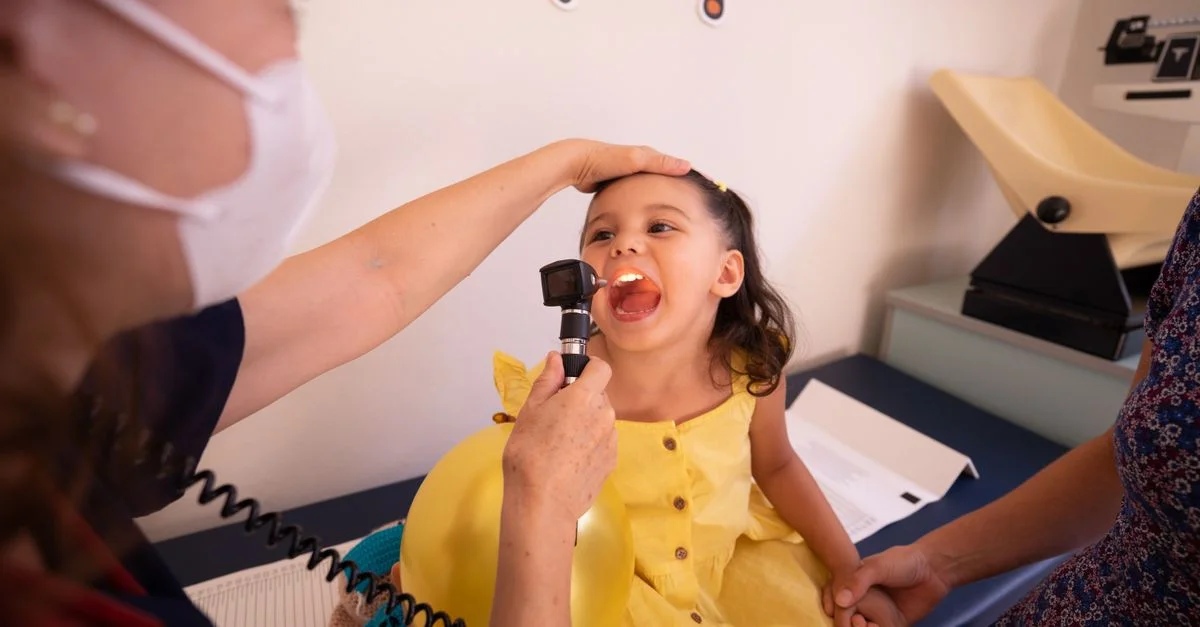 Pediatra examina a un niño sonriente en una clínica de salud. Entorno brillante con una atmósfera amigable.