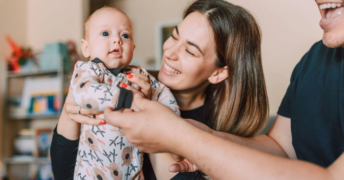 Un momento familiar alegre con los padres sosteniendo a su bebé en casa, mostrando amor y unidad.