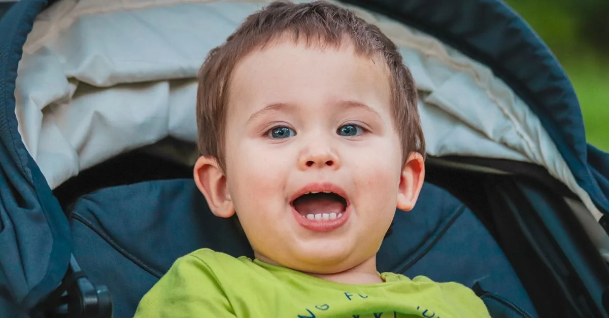 Un tout-petit souriant dans une poussette profitant d'une journée ensoleillée à l'extérieur, affichant innocence et joie.