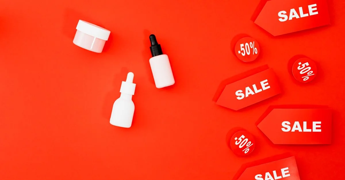 Vue de dessus des produits de beauté et des étiquettes de vente sur un fond rouge vibrant.